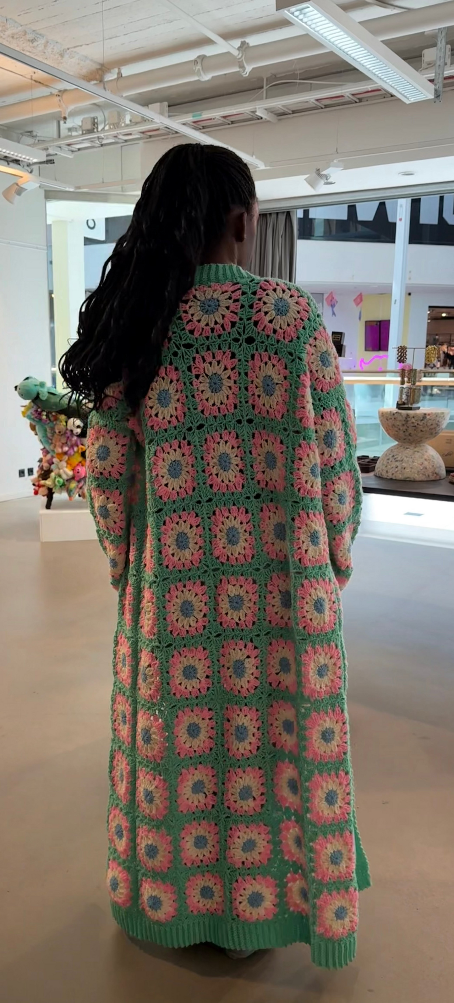 Person wearing a colorful crochet cardigan in an indoor setting